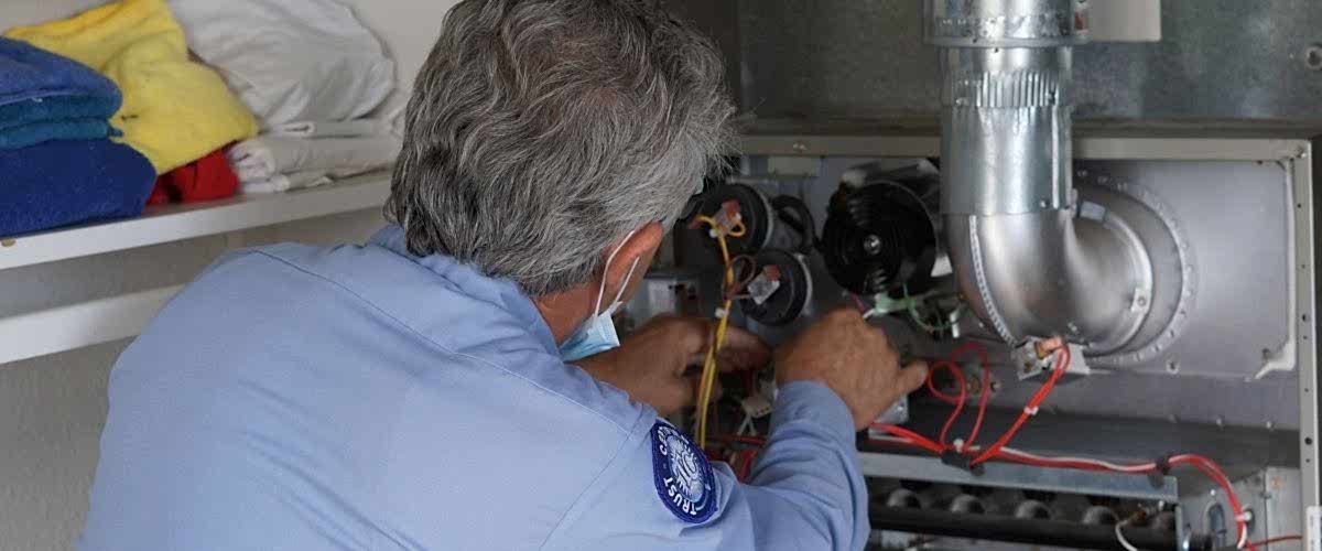 an HVAC professional with a light blue uniform from Brody Pennell is working on a heating system in a home in Southern California